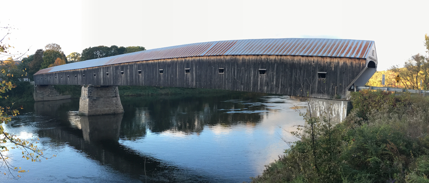 A train crossing a bridge over a body of water

Description automatically generated